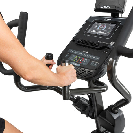 Close-up of a person using a Spirit exercise bike with a digital display on a white background