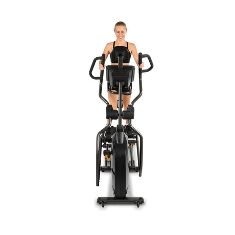 Woman exercising on a black elliptical machine against a white background
